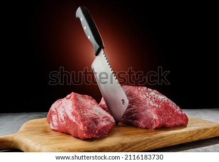 Raw meat cut in two with a chef's hatchet. Royalty-Free Stock Photo #2116183730