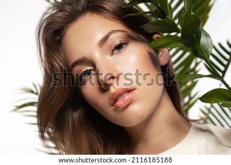 Beautiful woman with perfect  skin and natural make-up holding tropical   leaves Royalty-Free Stock Photo #2116185188