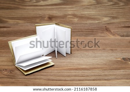 Two open blank pages miniature books on a wooden table.