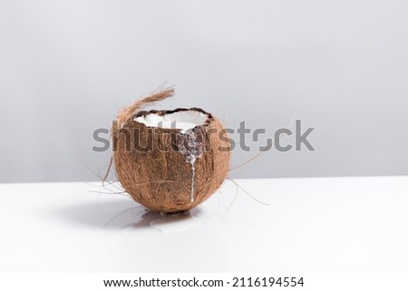 Coconut full of milk spilling onto a white table