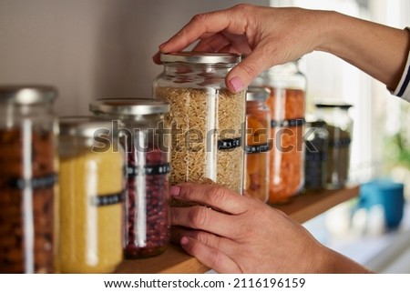 Woman Reusing Glass Jars To Store Dried Food Living Sustainable Lifestyle At Home Royalty-Free Stock Photo #2116196159