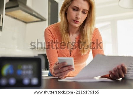 Smart Energy Meter In Kitchen Measuring Electricity And Gas Use With Woman Looking At Bills With Calculator Royalty-Free Stock Photo #2116196165