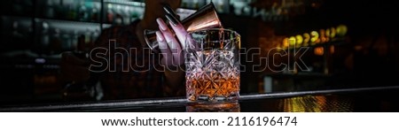 Bartender hand pouring whiskey on glass in bar Royalty-Free Stock Photo #2116196474