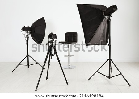 Empty chair in front of camera and professional lighting equipment indoors. Photo studio set