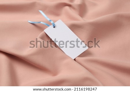 Blank white tag on pink fabric. Space or text