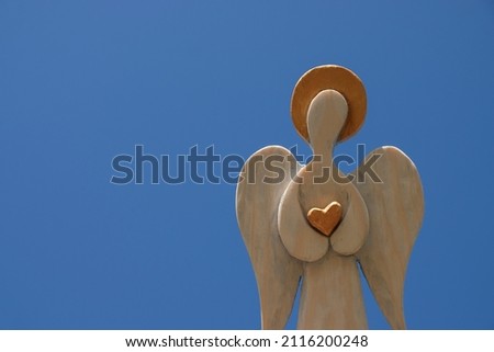Wooden angel on blue sky background. Religious postcard. Copy space.