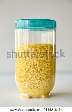 bright yellow millet in a transparent container on a light background