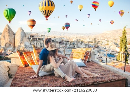 Happy couple on a rooftop in Cappadocia with hot air balloons in the background. Hot air balloon flights in Turkey Royalty-Free Stock Photo #2116220030