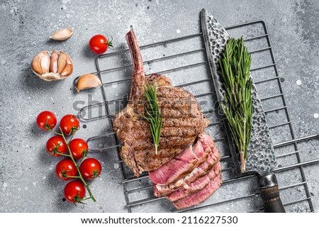 BBQ roasted sliced rib eye Tomahawk beef steak on grill. Gray background. Top view