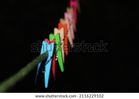 Rows of colorful tongs made of wood clamped on rope