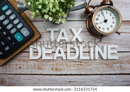 Tax Deadline alphabet letters with calculator and alarm clock on wooden background Royalty-Free Stock Photo #2116231724