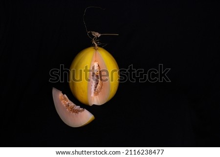 picture of golden melon with red flesh on a black background