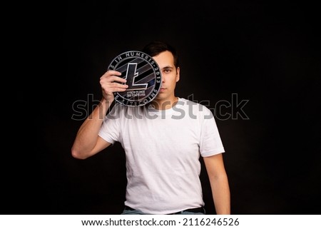 A man holds a litecoin coin in his hands as a symbol of technology. Image on black background