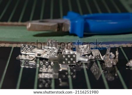 Metal clamps with teeth for connecting wires to a warm, filmy floor. There are pasatizhi in the background, blurred foreground and background - soft focus. Royalty-Free Stock Photo #2116251980