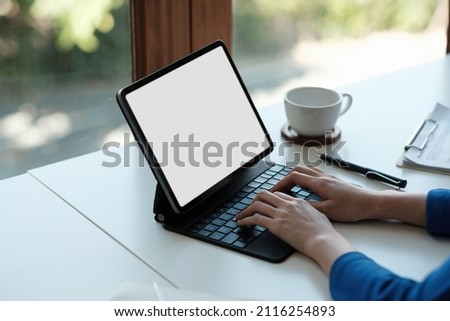 Mockup image of a woman using and touching on laptop touchpad with blank white desktop screen on wooden table