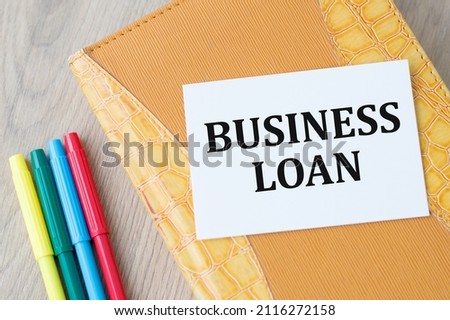 Business card with text Business Loan lies on a notebook on a wooden background, financial concept