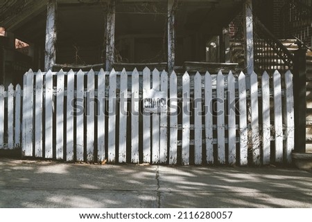 Chaos, white picket fence in front of abandoned home