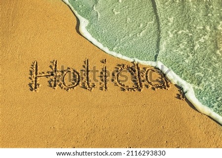 The word holiday written in the sand
