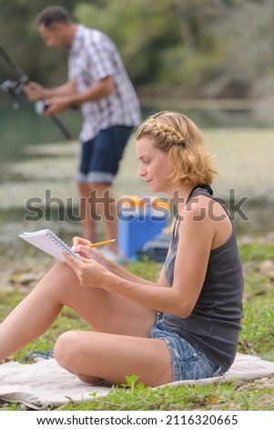 artist draws a picture while boyfriend is fishing