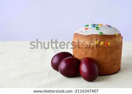 Traditional Easter cake with decorative glaze. Orthodox food after fasting on the Easter holiday. Red-painted chicken eggs on a light tablecloth