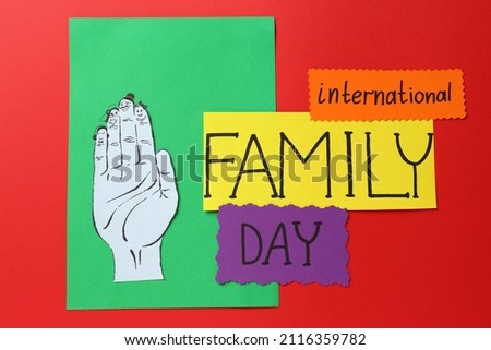 Paper cards with text International Family Day and hand cutout on red background, flat lay Royalty-Free Stock Photo #2116359782