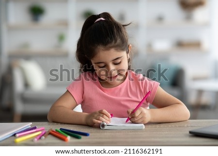 Portrait Of Cute Little Preteen Girl Drawing With Colorful Pens While Sitting At Desk At Home, Beautiful Arab Female Child Writing In Notepad, Small Kid Doing School Homework, Copy Space
