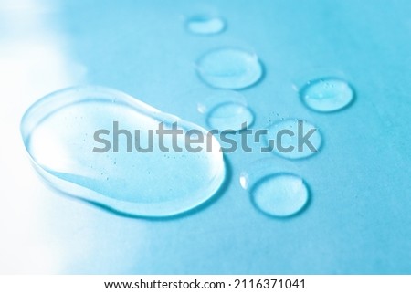 Gel transparent drops of acid on a colored background. Texture of a cosmetic product for body care, moisturizing and cleansing, close-up, top view.