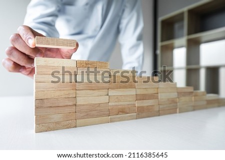 Risk To Make Business Growth Concept With Wooden Blocks, hand of businessman has piling up and stacking a wooden block, Alternative risk concept, plan and strategy in business. Royalty-Free Stock Photo #2116385645