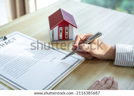 Estate broker agent presenting and consult to customer to decision making sign insurance form agreement, home model, concerning mortgage loan offer.