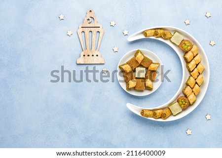 Ramadan kareem with baklava sweets  arranged in shape of crescent moon. Iftar food concept. Top view, copy space Royalty-Free Stock Photo #2116400009