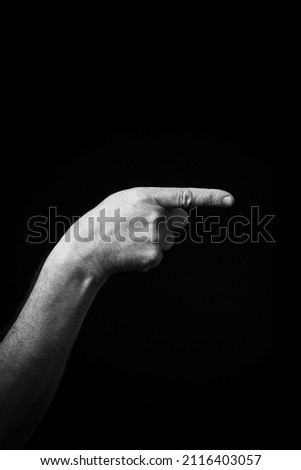 Dramatic black and white  image of a male hand fingerspelling the Chinese sign language letter 'G', isolated against a dark background