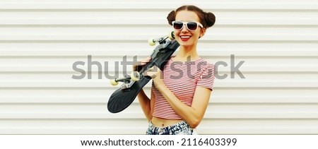 Summer portrait of cheerful smiling young woman posing with skateboard on white background