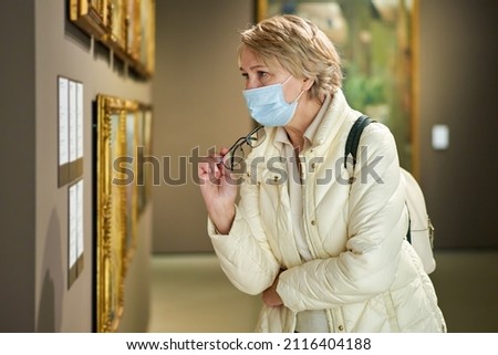 woman looking at modern painting in art gallery