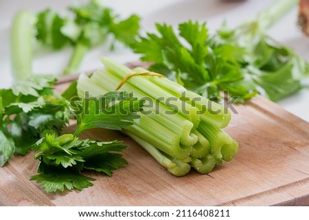 Celery stems and leaves on wooden cutting board Royalty-Free Stock Photo #2116408211