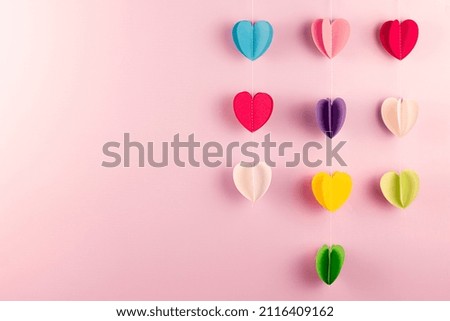 Different colors paper hearts on pink background with copy space. Valentine’s Day, mother day and holiday greeting card. mock up.