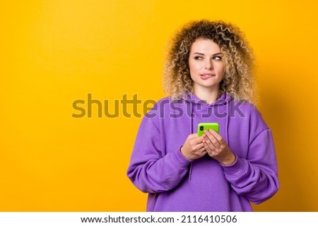 Photo of young lady look empty space hold mobile guess look empty space think isolated over yellow color background