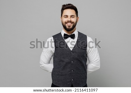 Young barista male waiter butler man wear white shirt vest elegant uniform work at cafe looking camera waiting for order isolated on plain grey background studio portrait. Restaurant employee concept Royalty-Free Stock Photo #2116411097