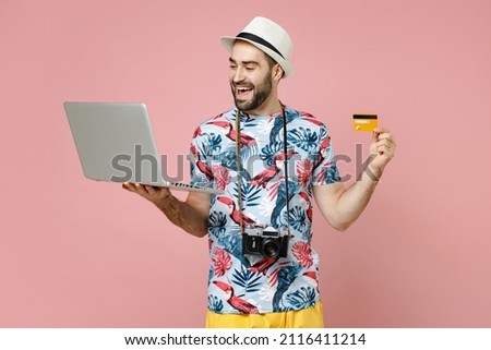 Funny traveler tourist man in summer clothes hat using laptop pc computer booking hotel hold credit bank card isolated on pink background. Passenger traveling on weekends. Air flight journey concept Royalty-Free Stock Photo #2116411214