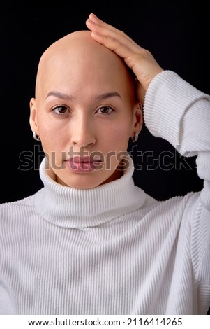 bald lady on black studio background, looks at camera, confident. she feels awkward due to falling hair. concept of oncology and effects of chemotherapy. portrait copy space. people, healthcare