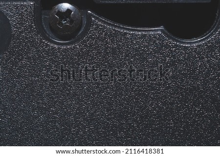 Black plastic surface with screw. detail of plastic cassette close up