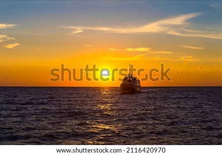 A ship at sunset on the sea horizon. Ship silhouette at sunset. Sunset sea ship silhouette view. Sea sunset ship Royalty-Free Stock Photo #2116420970