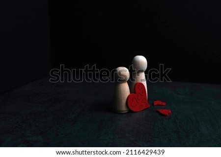 Large wooden peg and smaller peg with red love hearts on black background. Concept of love and valentines day. 