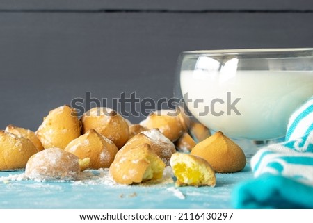 
Shortbread cookies consisting of butter, flour, and jam filling, view of baked sweet cookies and a glass of milk on a wooden background, selective focus