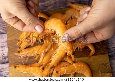 close-up of boiled shrimps that are cleaned from the shell of women's hands