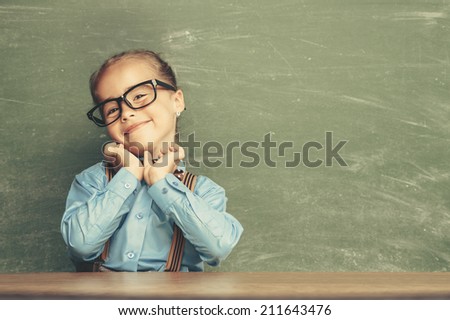 Beautiful smiling girl against chalkboard. School concept