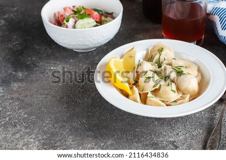 Homemade ravioli stuffed with chicken meat in a white plate on a grey background. Royalty-Free Stock Photo #2116434836