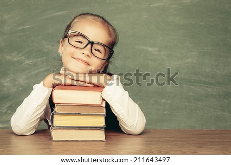 Beautiful smiling girl against chalkboard. School concept