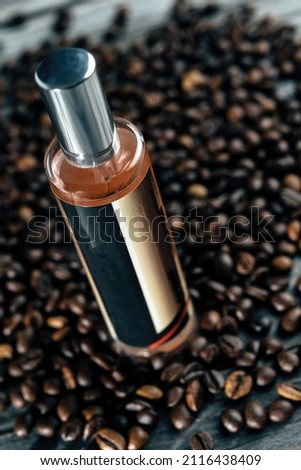 A bottle of coffee aroma lies on top of a pile of roasted coffee beans. Advertising photography.