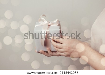 Close up shot of woman hands holding surprise gift package box on pink pastel background with copy space. Valentine's gift