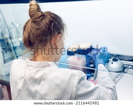A female PhD student carrying out a cytotoxicity assessment of a new drug molecule using an MTT assay. This might be a part of drug discovery program at a pharmaceutical company.  Royalty-Free Stock Photo #2116445981